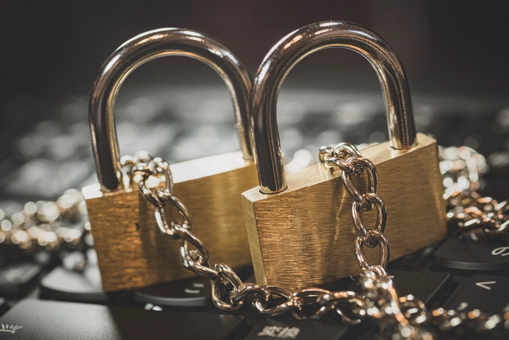 Two brass padlocks chained together on a laptop keyboard