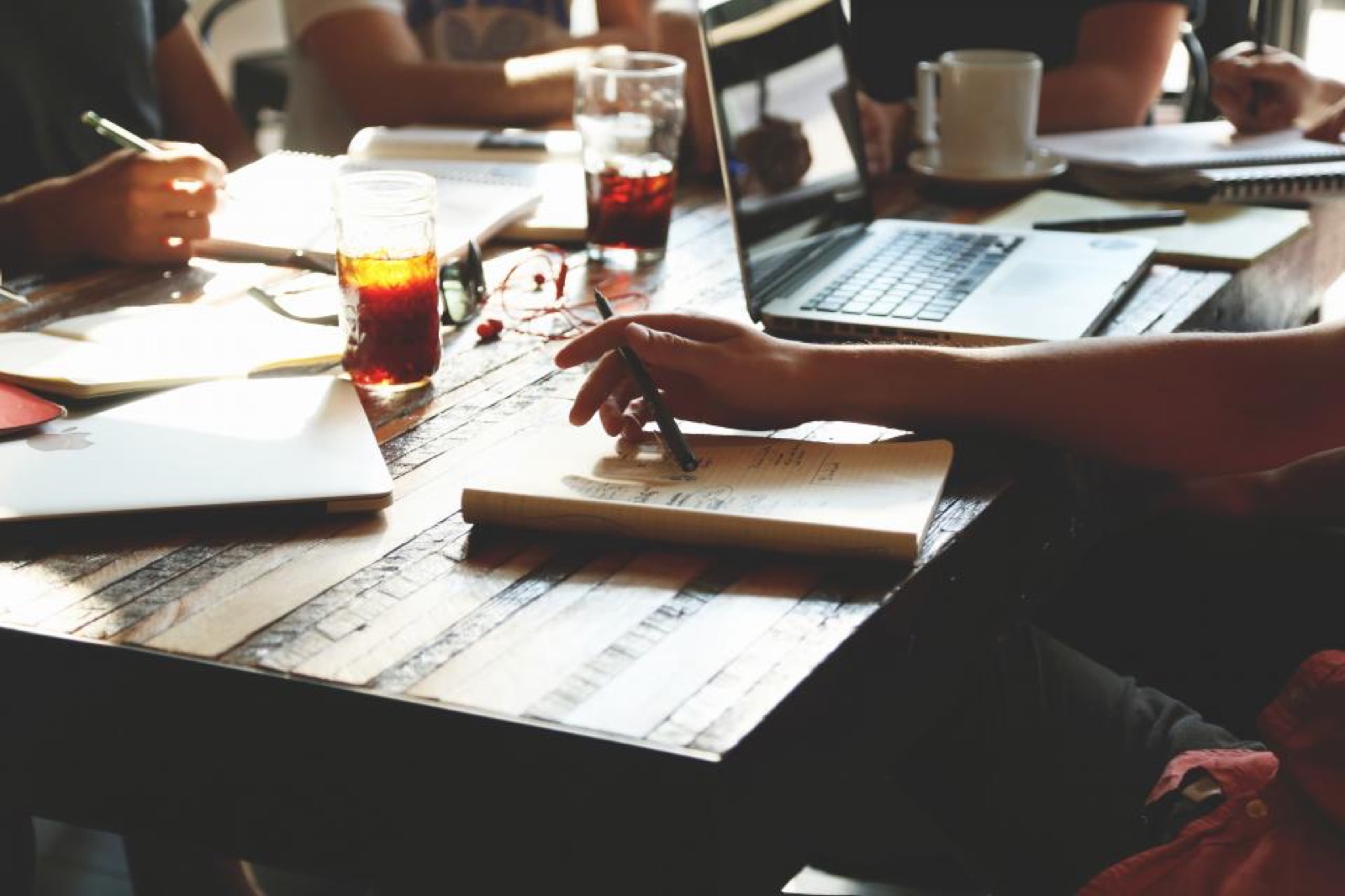 Team working together at a table with laptops and notebooks