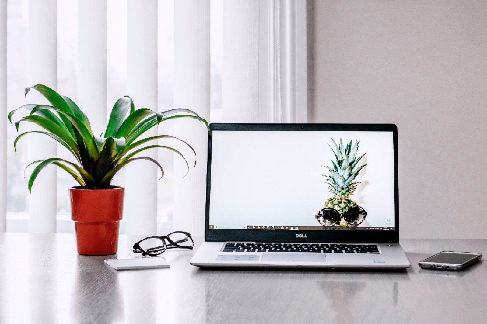 Laptop with a plant and glasses on a bright home-office desk