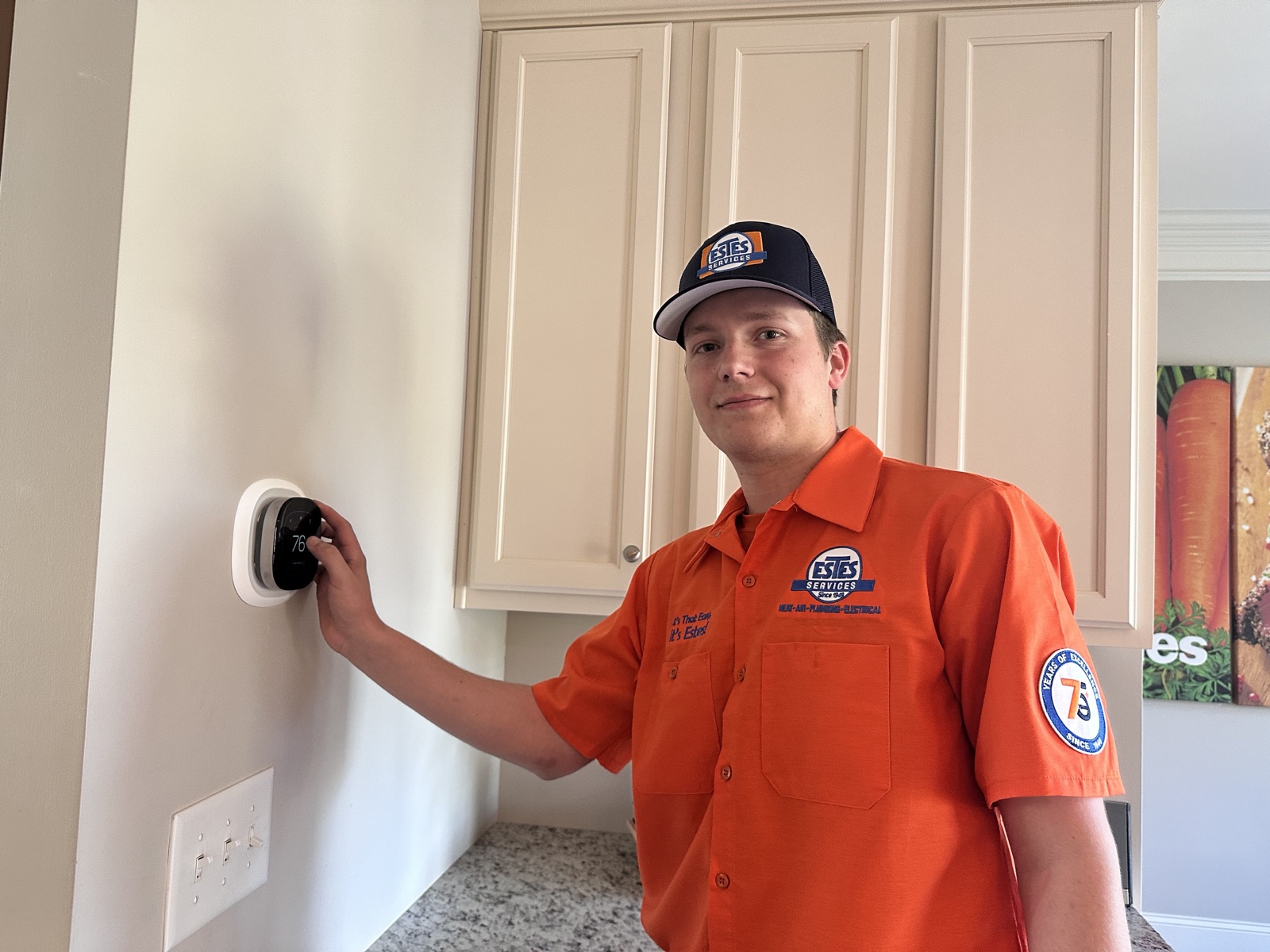 HVAC technician in uniform adjusting a wall thermostat in a home