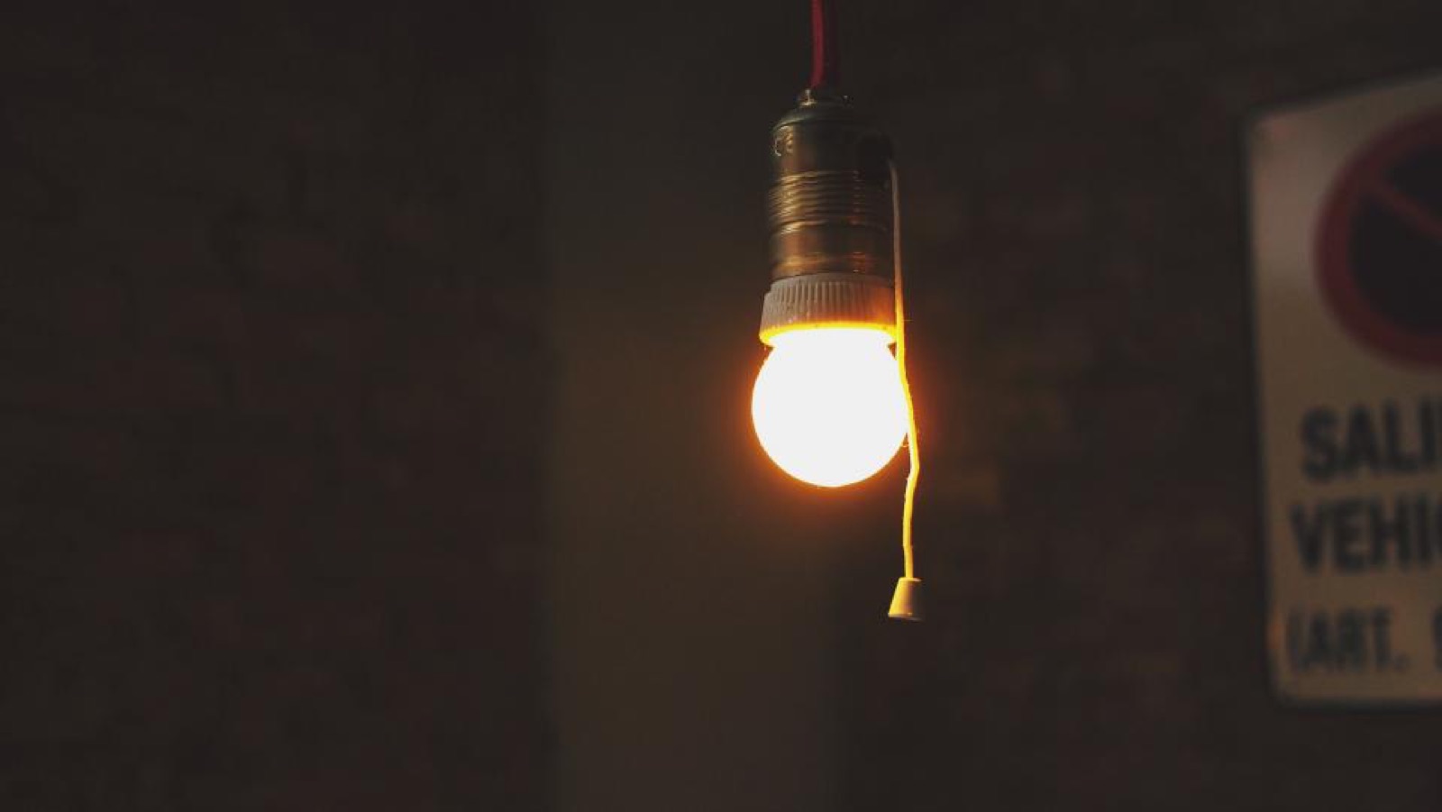 Glowing light bulb hanging in a dark room
