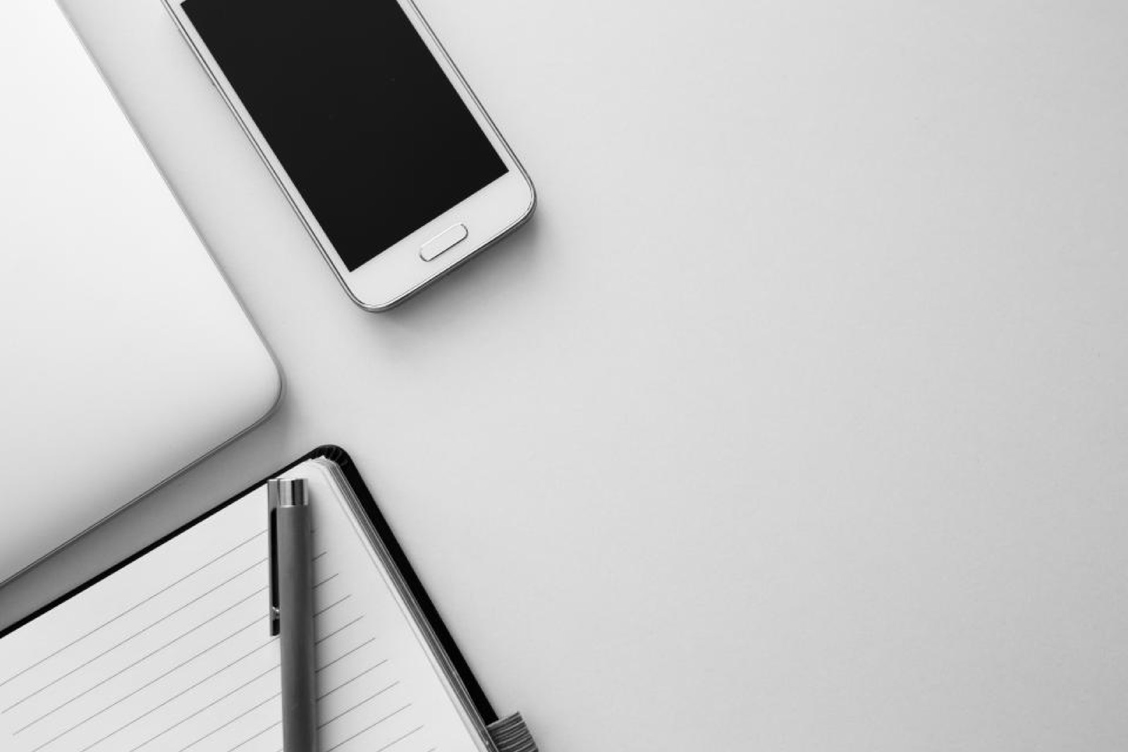 Smartphone resting on a desk next to a notebook and pen