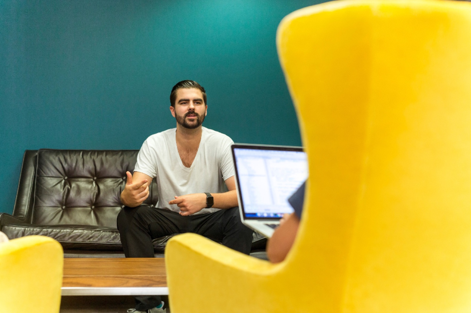 Man talking in a casual office interview setting with a laptop