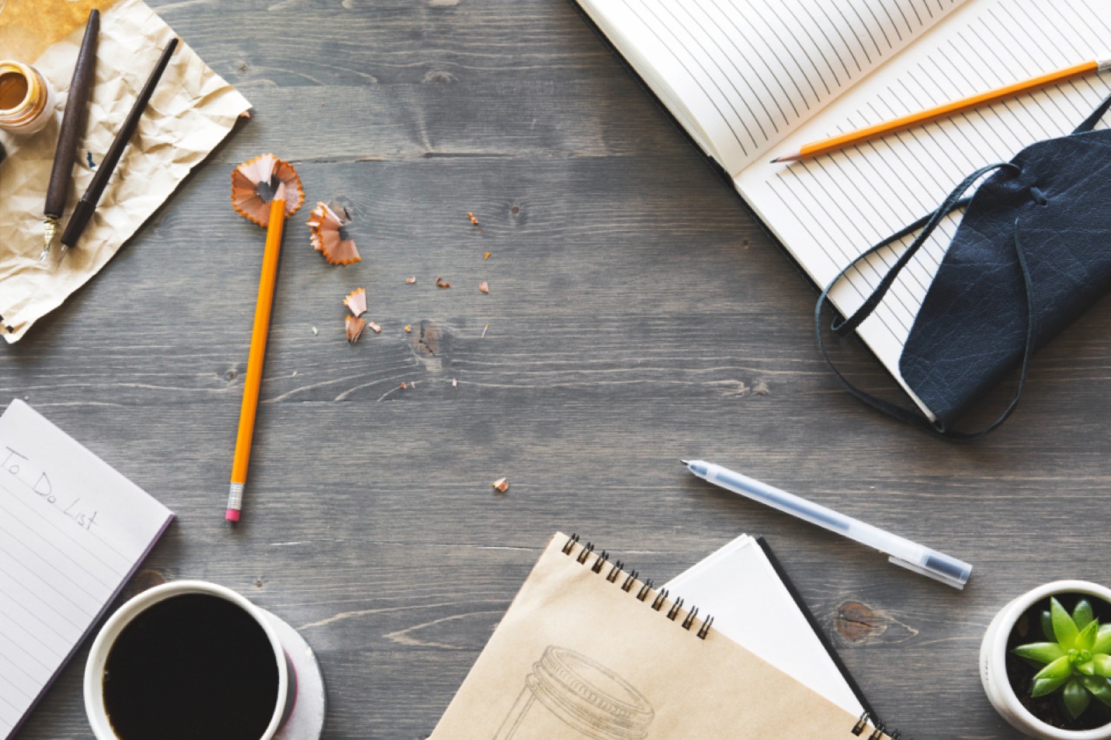 Creative workspace with notebooks, pencils and coffee from above